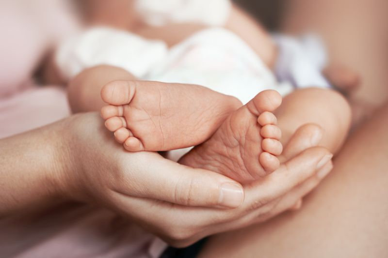 Feet of newborn baby on mother's palm